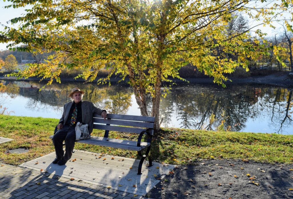 man sitting on bench next to river