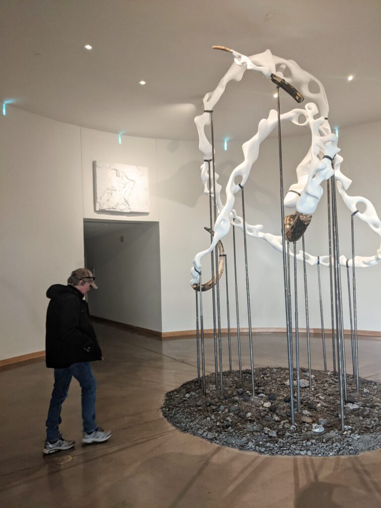 man standing in front of sculpture in art gallery